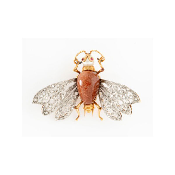 Broche representando mosca en oro amarillo y alas en oro blanco con cuerpo en piedra venturina, perla cultivada representando cabeza, y rubís en los ojos, alas con decoración de flores con 2 diamantes talla brillante y cuajado de diamantes.