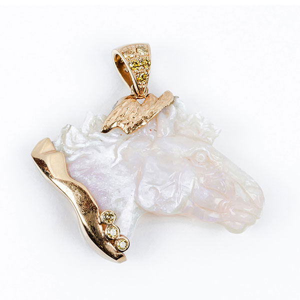 Original colgante, 'cabeza de caballo' tallada en ópalo blanco iridiscente, en sólida montura de oro amarillo,  decorada con diamantes
