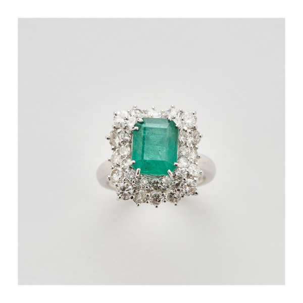 Sortija rosetón en oro blanco con esmeralda talla octogonal y doble orla de diamantes talla brillante engastados en garras.