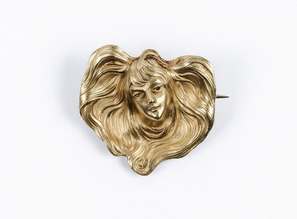 Broche-alfiler modernista antiguo, &#039;art noveau&#039;, en oro amarillo con rostro de mujer y melena al viento. C. 1900.