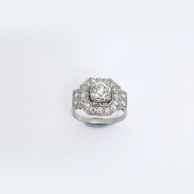 Bella sortija vintage &#039;art-decó&#039; en montura de platino u oro blanco, con un limpio y blanco diamante, talla brillante antigua orlado de diamantes