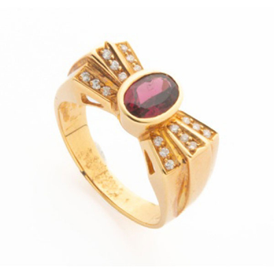 Sortija en oro amarillo con piedra granate central y 3 filas de diamantes talla brillante con un peso total de 0,38 cts. representando lazo.