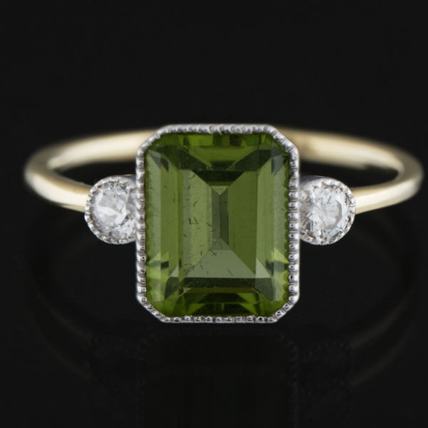 Anillo en oro blanco y oro amarillo de 18 kt con peridoto central de dos brillantes.