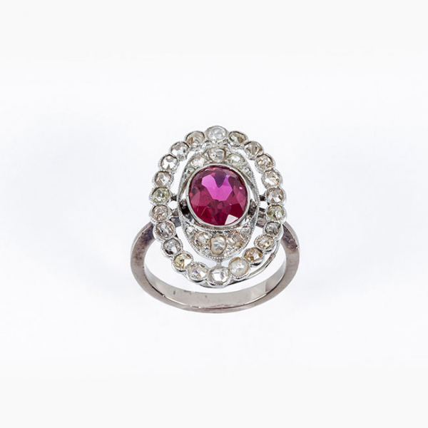 Sortija lanzadera estilo art-dec&oacute; en oro blanco 18 K, con una piedra roja, talla oval central, y doble orla calada de diamantes 