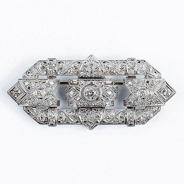 Alfiler-plaqueta estilo 'art-decó', años 40-50, en montura calada de oro blanco, con diamante central, talla brillante