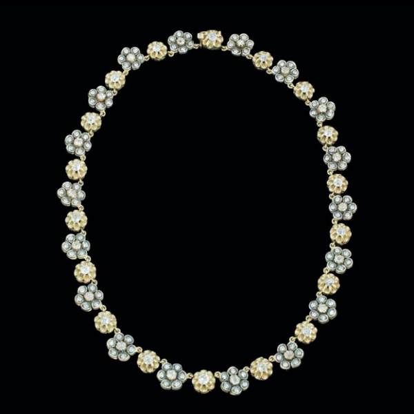 Collar de oro amarillo de 14 K. con vistas de plata en rosetones de diamantes y en garras formando una flor.