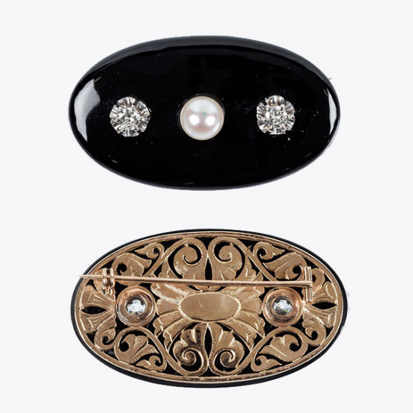 Alfiler antiguo formado por placa oval de &oacute;nix negro sobre oro amarillo 18 K, con celos&iacute;a calada y dos centros de blancos diamantes
