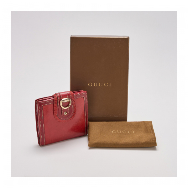 GUCCI. Billetera en cuero rojo con cierre de botón a presión con volante decorativo y logotipo en metal dorado.
