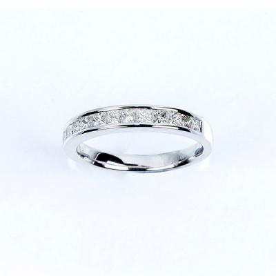Anillo media alianza en oro blanco 18 K, con banda de limpios y blancos diamantes talla princesa.