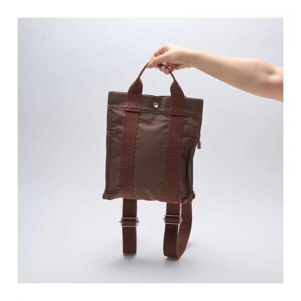 HERMÈS. Mochila modelo «Herline» en lona de tonalidad marrón con asas y correas ajustables