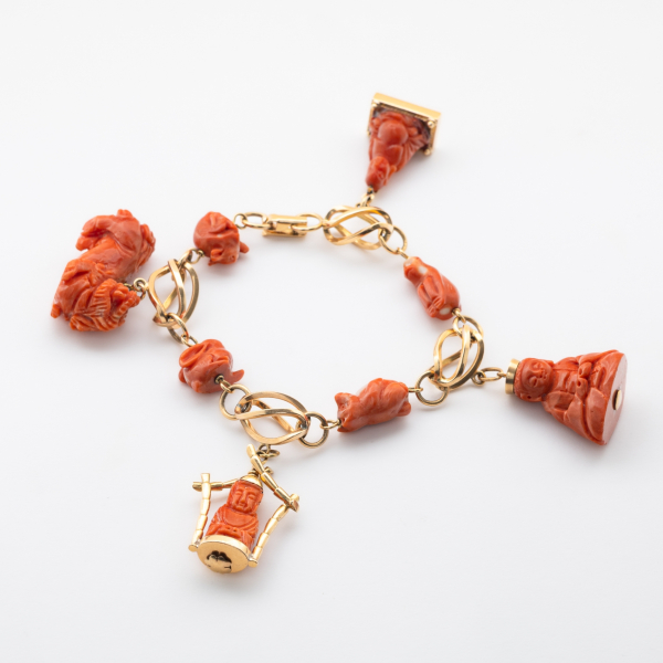 Pulsera con eslabones tipo jaula en oro rosa alternados por figuras de animales tallados en coral.  