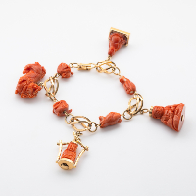Pulsera con eslabones tipo jaula en oro rosa alternados por figuras de animales tallados en coral.  