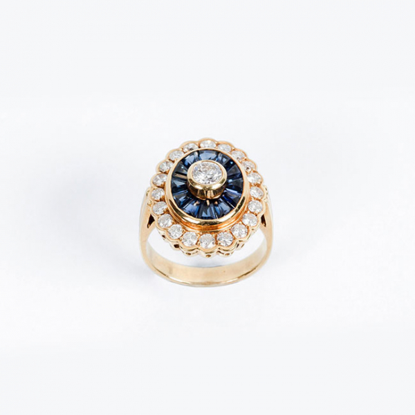 Sortija de alta joyería, años 90, en sólida montura de oro amarillo 18 K, con un limpio y blanco diamante central, talla brillante y zafiros finos azules 