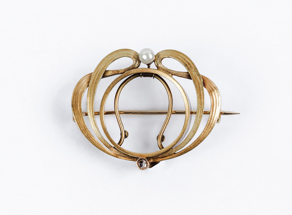 Antiguo alfiler portafotos modernista en oro amarillo, diseño floral calado decorado con lazadas superpuestas, con frente gallonado, rematadas con una perlita y un diamante en chatón. C 1900.